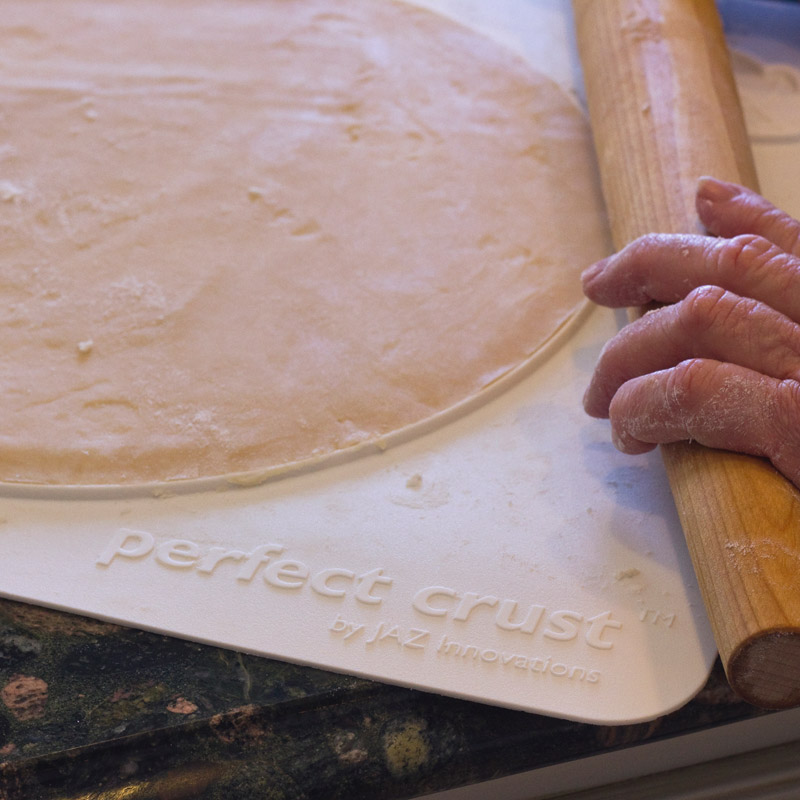 Rolling out pie dough using rolling pin and Perfect Crust™ Pie Mat