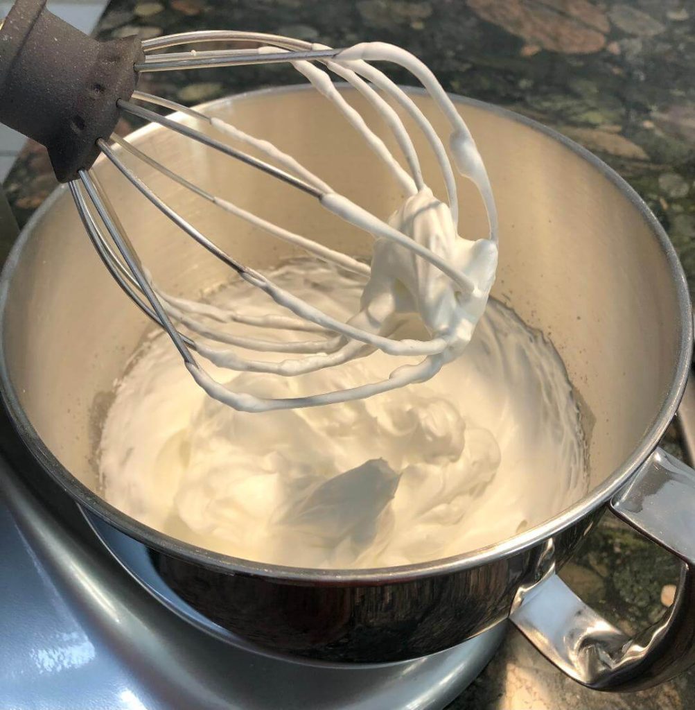 Egg whites and cream of tartar in the bowl of a stand mixer fitted with the whisk attachment being beaten for Meringue topping.